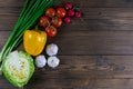 Green onions, yellow peppers, cherry tomatoes, slot and cabbage on dark wooden table. Top views, close-up with clear space Royalty Free Stock Photo