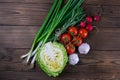 Green onions, yellow peppers, cherry tomatoes, slot and cabbage on dark wooden table. Top views, close-up Royalty Free Stock Photo