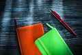 Green and orange notebooks on wooden board