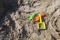 Green, orange, yellow plastic toy shovels on the beach sand or sand box