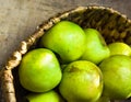 Green organic apples in wicker basket on rustic wooden table in sunlight leaks. Local produce healthy plant based diet vitamins Royalty Free Stock Photo