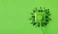 Green outlet or wall socket and power cord with fresh leaves top view. Renewable and saving energy, eco and natural resources Royalty Free Stock Photo