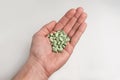 Green oval pills on the palm on a gray background