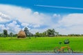 Green paddy rice field with the straw, animal feed,the bicycle, the beautiful sky and cloud in Thailand Royalty Free Stock Photo