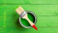 A green paint can with a red handle is sitting on a green surface Royalty Free Stock Photo