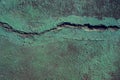 Green painted asphalt with earthquake crack photo. Cement floor stain and grit closeup. Urban texture