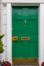 Green painted front door with white frame and brass furniture Royalty Free Stock Photo