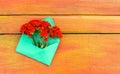 Green paper envelope with fresh garden red lychnis flowers on wooden background. Festive floral template. Greeting card design. To