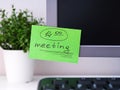 A green paper notes with the reminder 14-00 Meeting on it sticked on to a monitor at an office workplace Royalty Free Stock Photo