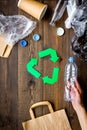 Green paper recycling sign among waste materials paper, plastic, polyethylene on dark wooden background top view copy Royalty Free Stock Photo