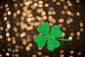 Green paper shamrock over festive lights Royalty Free Stock Photo