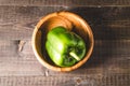 Green paprika on a wooden bowl/Green paprika pepper on a wooden bowl over dark background. Top view