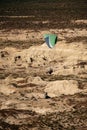 Green paraglider above desert badlands