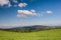 Green pasture and forest under blue sky with clouds Royalty Free Stock Photo