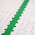 The green path is laid on the platform of a white folded jigsaw puzzle. Texture image with copy space for text Royalty Free Stock Photo