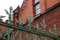 Green patina copper fence in front of old green orange red brick wall of an old building. Architecture detail of Klaipeda city old Royalty Free Stock Photo
