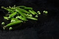 Bright green pea pods covered with water drops on a black background. There are separate peas. Royalty Free Stock Photo