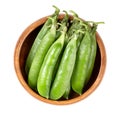 Fresh pea pods, containing green peas, in a wooden bowl Royalty Free Stock Photo