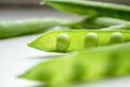 Green peas on the table. On a white background is an open pod of green peas. Green pea pods with young beans. Royalty Free Stock Photo