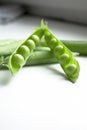 Green pea pods with young beans. Green peas on the table. On a white background is an open pod of green peas. Royalty Free Stock Photo