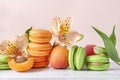 Green, peach macaroon cookies , yellow Alstroemeria flowers, fresh apricots on a beige