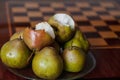 Green pears lie on plate next to chessboard Royalty Free Stock Photo
