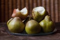 Green pears lie on plate. On top are bitten pears