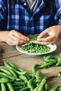 Green peas bowl wooden table Female hands clean green peas sitting wooden table kitchen close up Rustic style Royalty Free Stock Photo