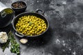 Green peas in a cast-iron bowl. Canned food. Black background. Top view. Copy space Royalty Free Stock Photo