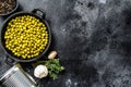 Green peas in a cast-iron bowl. Canned food. Black background. Top view. Copy space Royalty Free Stock Photo