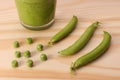 Green peas and and pea pods and green smoothie on wooden table Royalty Free Stock Photo