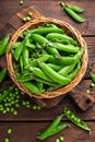 Green peas in pods and peeled in wooden bowl on table