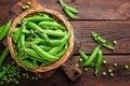 Green peas in pods and peeled in wooden bowl on table