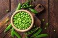 Green peas in pods and peeled in wooden bowl on table Royalty Free Stock Photo