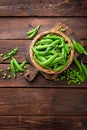 Green peas in pods and peeled in wooden bowl on table Royalty Free Stock Photo