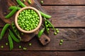 Green peas in pods and peeled in wooden bowl on table
