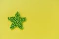 Green peas in the shape of a star on a yellow background Royalty Free Stock Photo