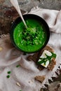 Green peas and spinach puree soup in a black bowl. Vegetarian cream soup on gray background. Healthy eating during quarantine Royalty Free Stock Photo