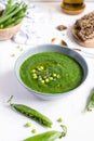 Green peas vegetarian soup in gray bow on white wooden table, seeds crackers - diet food, weight loss Royalty Free Stock Photo