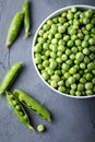 Green peas in white bowl with fresh pods. Top view. Royalty Free Stock Photo