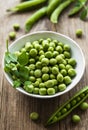 Green peas in white bowl with fresh pods