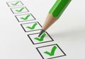 Green pencil marking a checklist with green checkmarks isolated on white background Royalty Free Stock Photo
