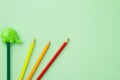 Green pencil sharpener and five pencils on a pale green background Royalty Free Stock Photo