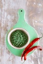 Green peppercorns in bowl and red chillies on green wooden board Royalty Free Stock Photo