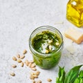 Green Pesto Sauce with Ingredients, Fresh Basil, Pine Nuts, Garlic and Cheese on light marbre background, space for text,