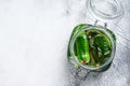 Green pickle cucumbers in a glass jar. Natural product. White background. Top view. Copy space