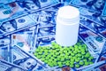 Green pills on the background of one hundred dollar bills. The concept of the expensive cost of healthcare or financing medicine. Royalty Free Stock Photo