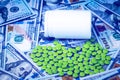 Green pills on the background of one hundred dollar bills. The concept of the expensive cost of healthcare or financing medicine. Royalty Free Stock Photo