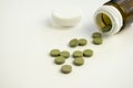 Green pills group are on the table. Brown plastic jar is near pills. Closeup, Royalty Free Stock Photo