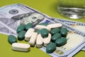 Green pills scattered on one hundred dollar bills. Cost of the healthy life concept Royalty Free Stock Photo